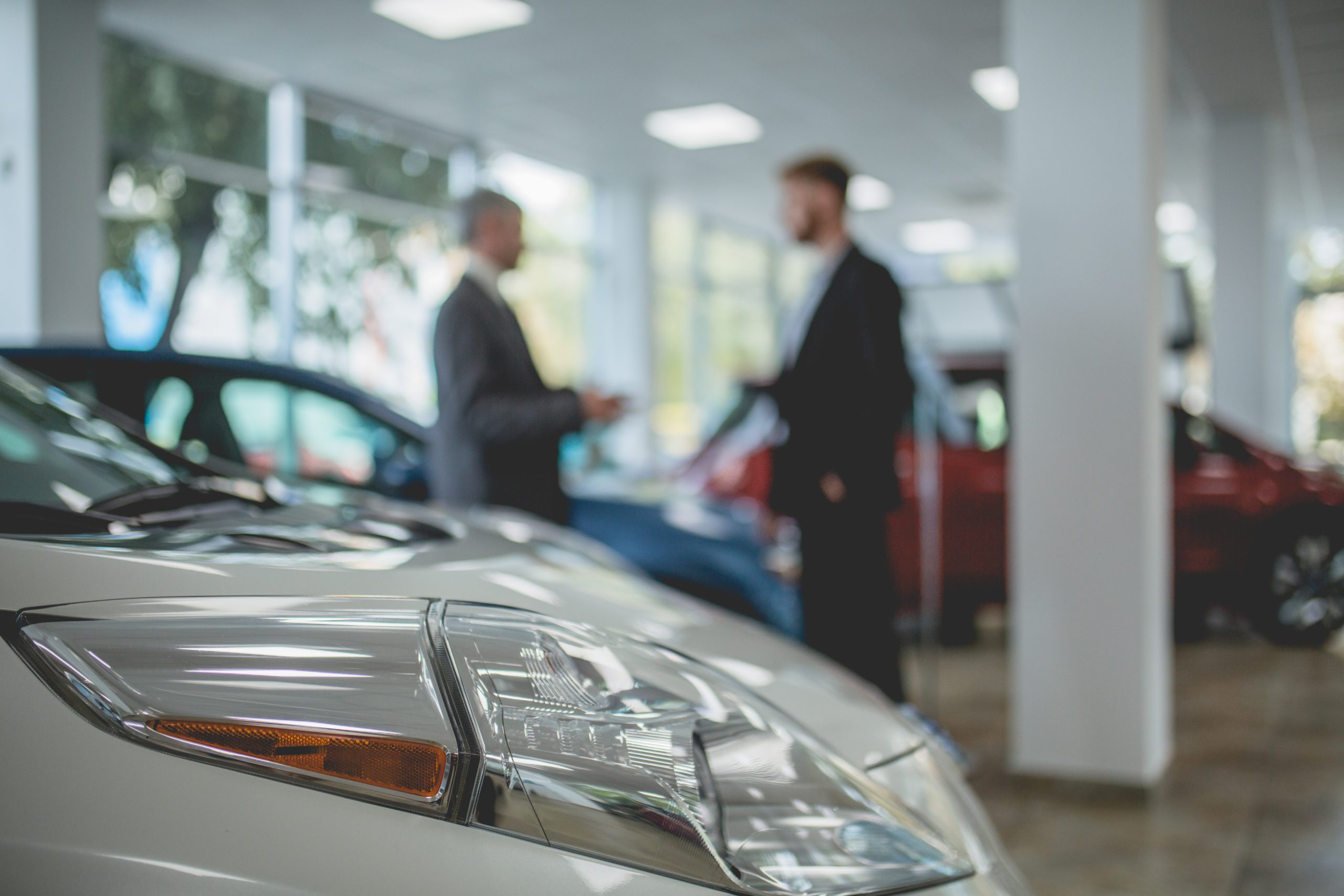Auto showroom, dealer talking with buyer. Electro cars in moderm vehicle salon.